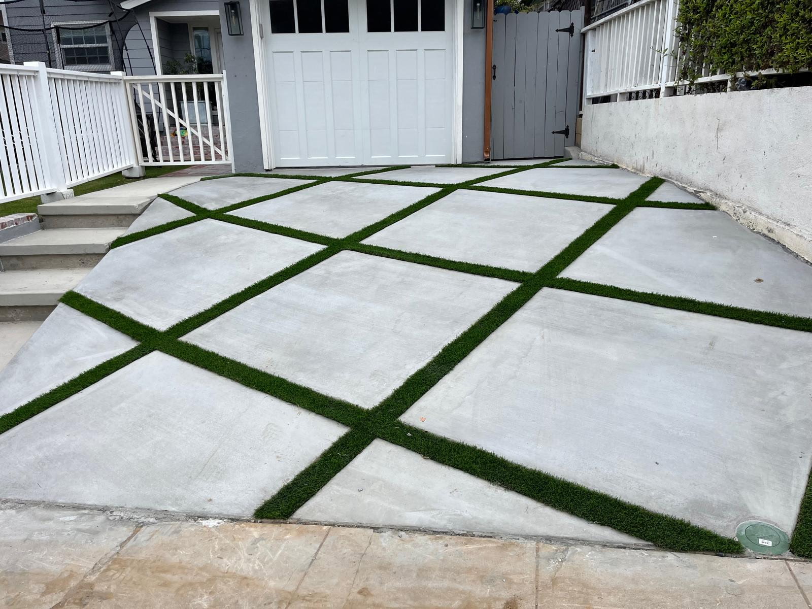 Fresh concrete driveway pad with turf joints leading to a San Diego garage